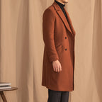 Person wearing a brown coat against a beige curtain background