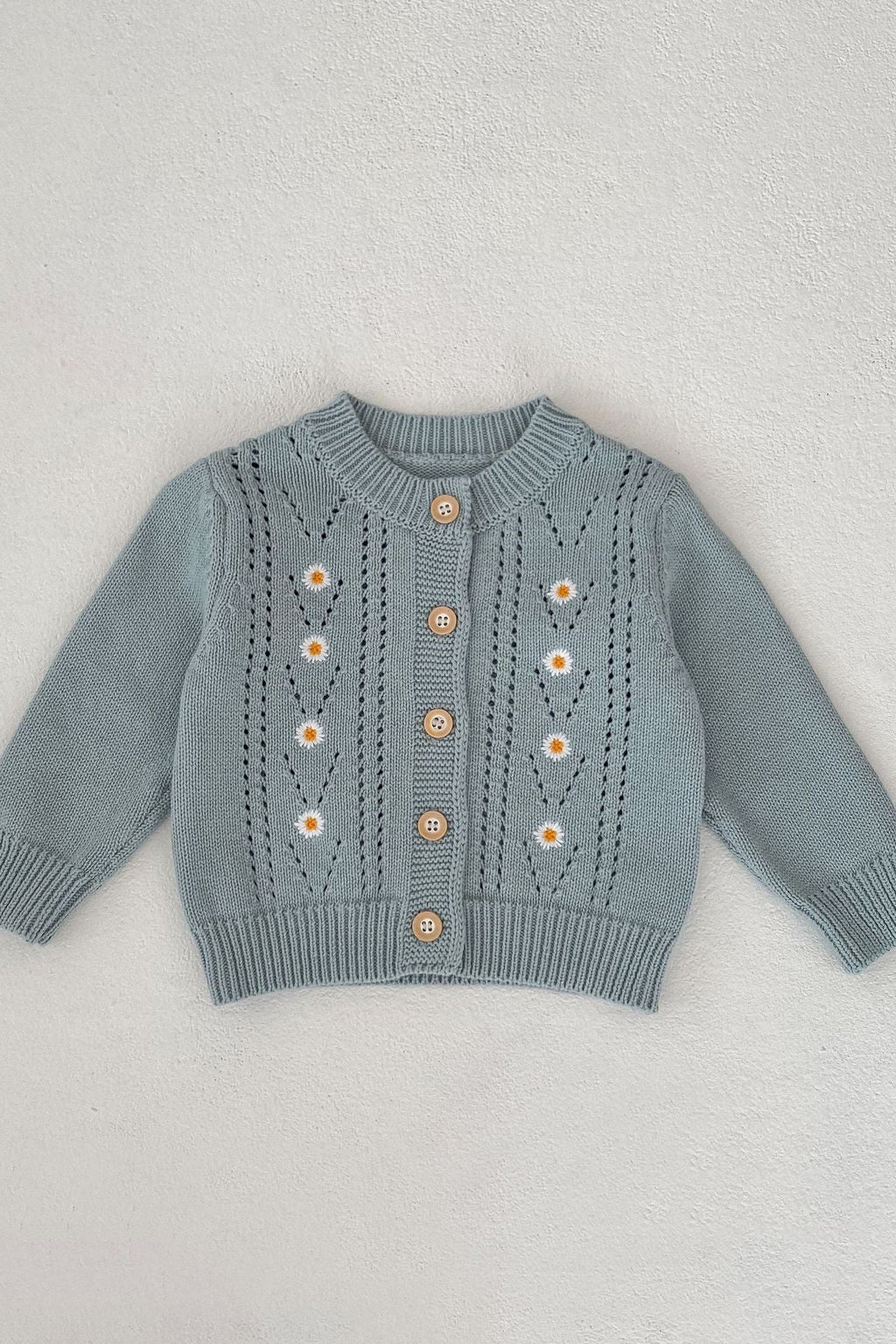 Blue children's sweater with floral patterns on a light gray background