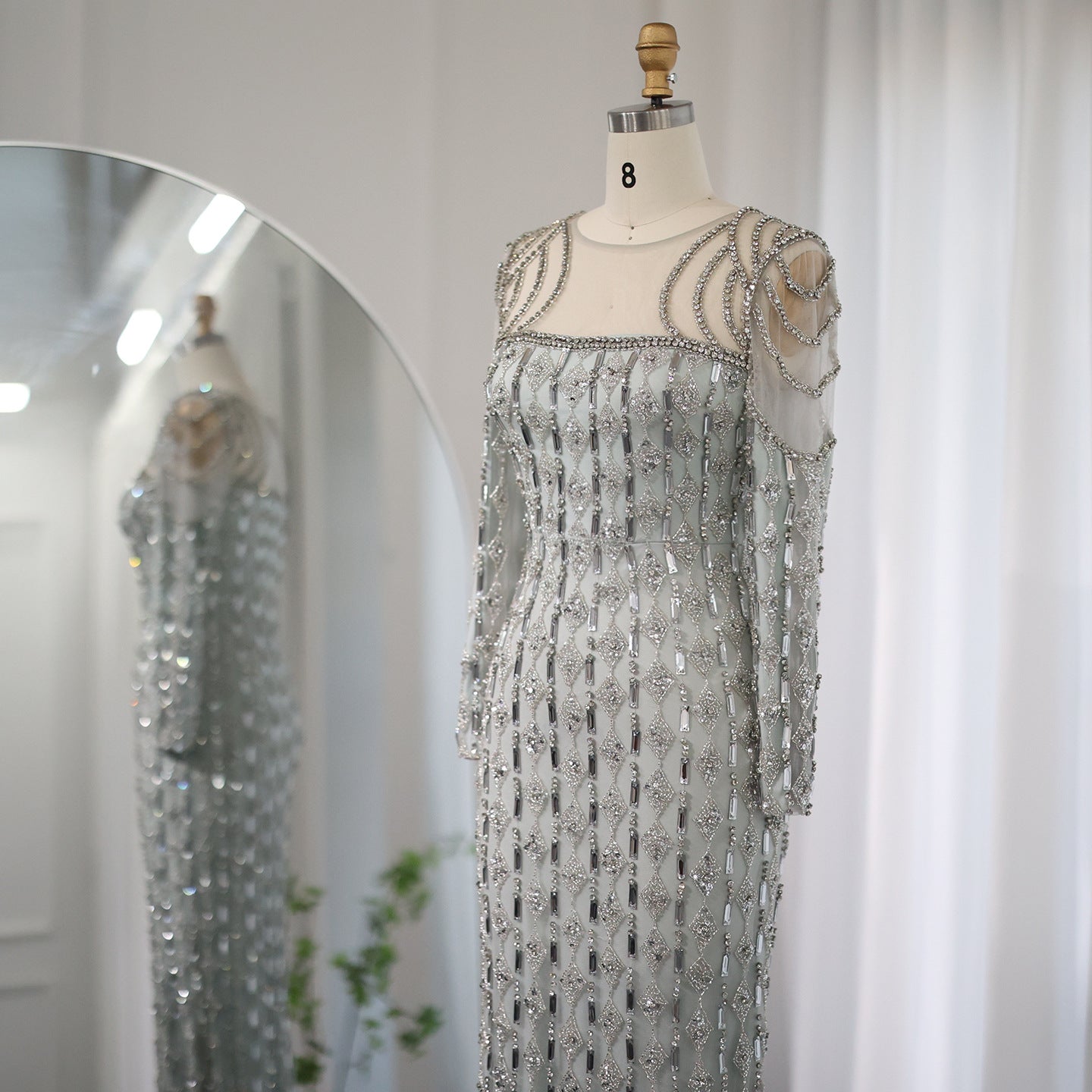 Silver beaded evening gown on a mannequin against a white background