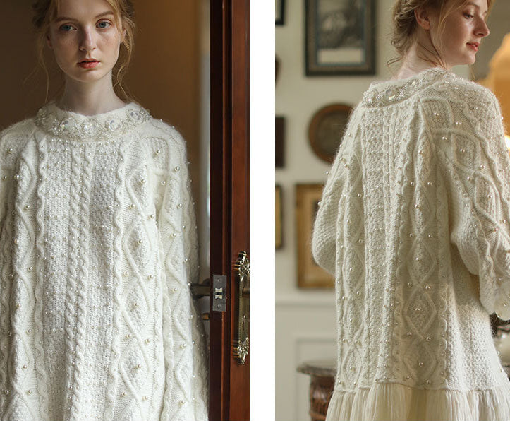 White cable knit sweater worn by a model indoors.
