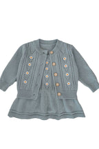 Light blue knitted dress with button details on a white background