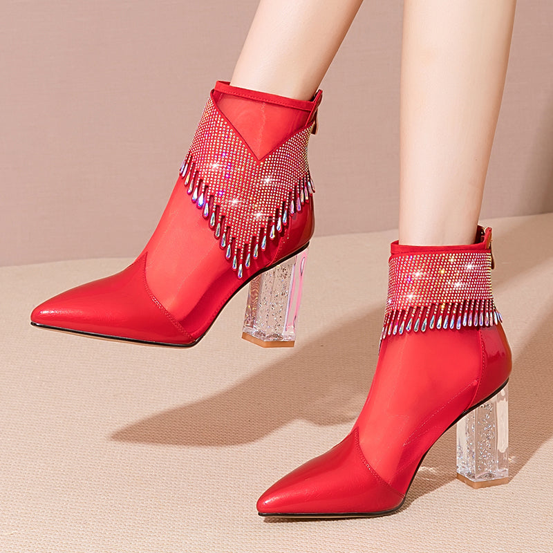 Red high-heeled boots with rhinestone embellishments on a beige background