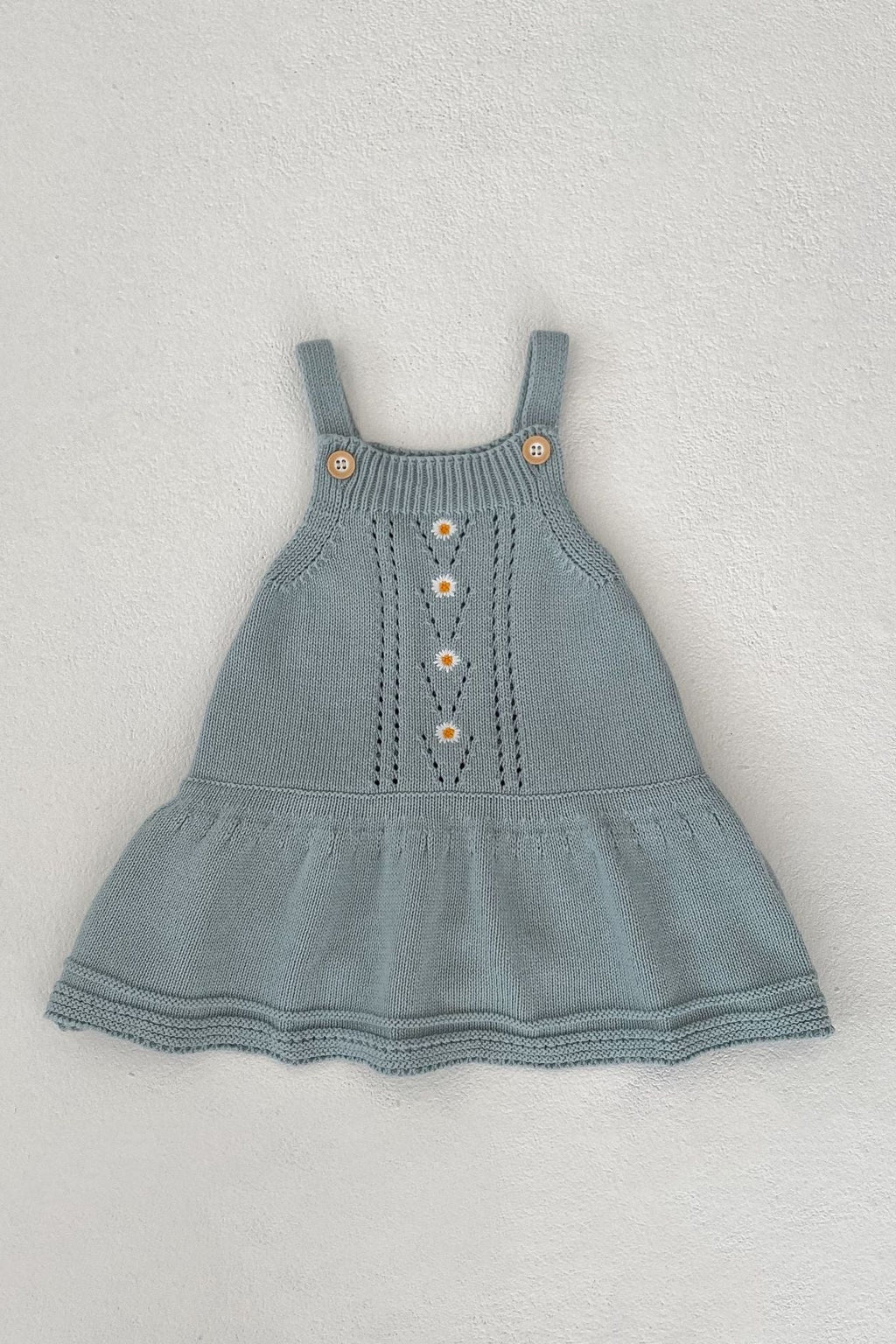 Blue knitted dress with button details on a light gray background