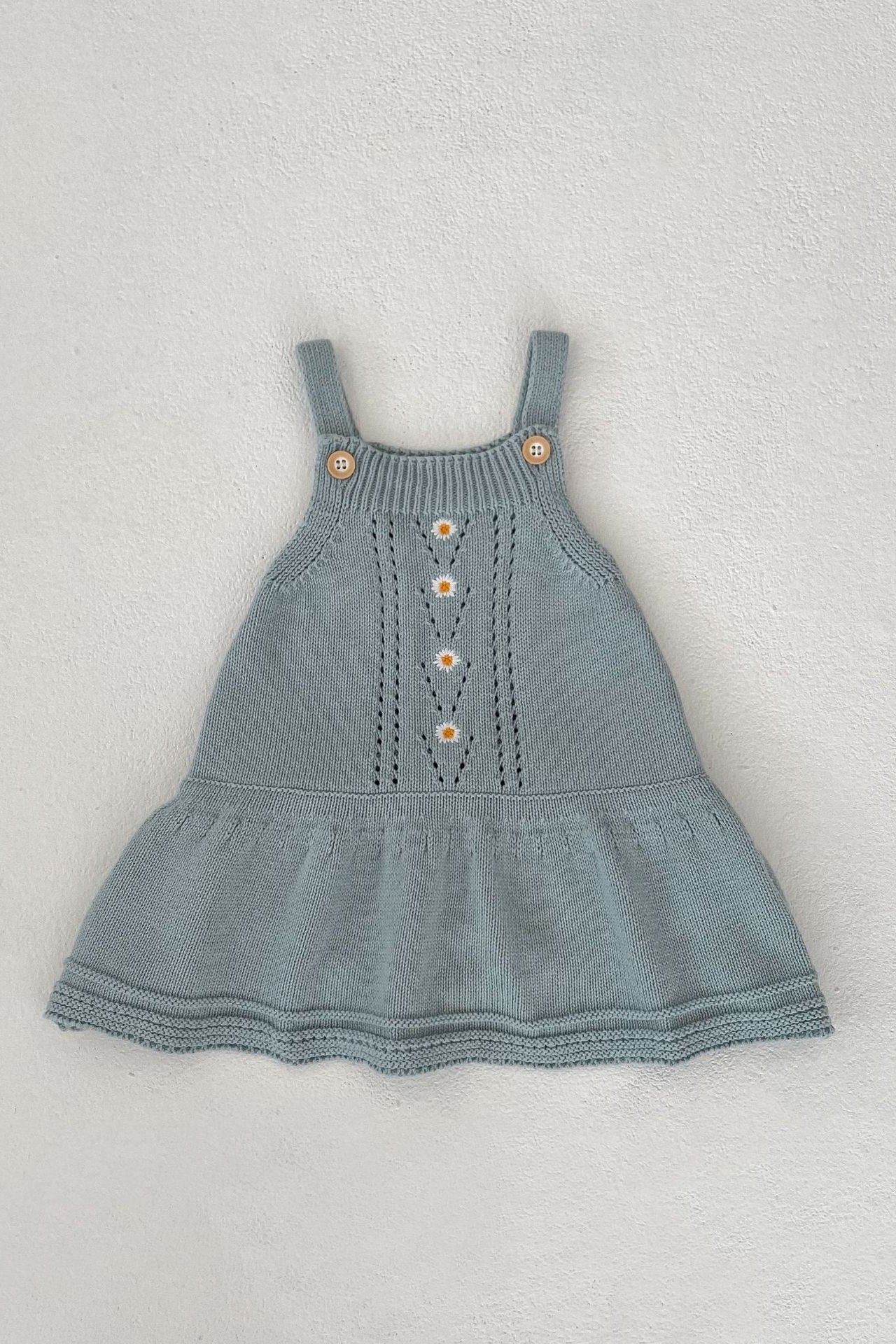 Blue knitted dress with button details on a light gray background