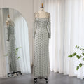 Elegant silver evening gown on a mannequin with a full-length mirror reflection in a room with white curtains.