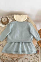 Light blue dress on a mannequin with a wicker basket and flowers in the background