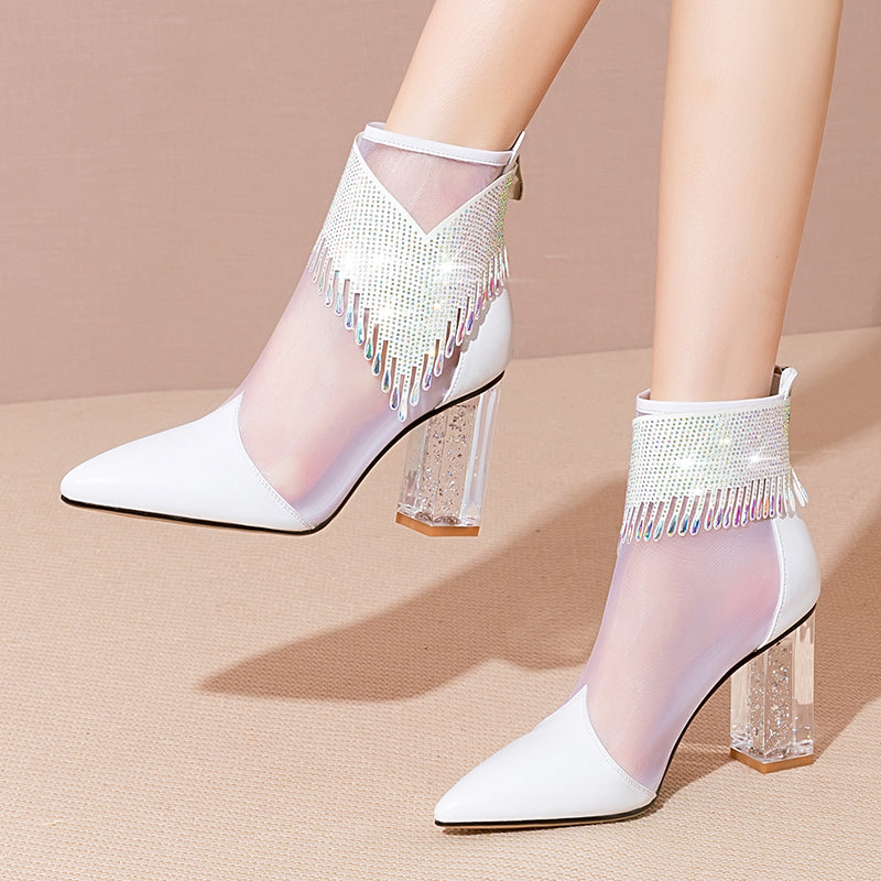 White high-heeled shoes with sheer mesh and crystal details on a beige background